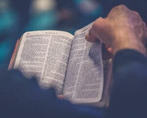 A picture of hands turning a page of the Bible.