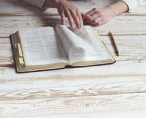 Picture of hands turning pages in a Bible with sticky notes marking a number of pages.