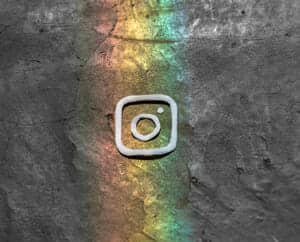 Picture of a rock with a rainbow reflection and strings made into an Instagram symbol placed on top of the reflection.