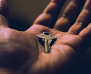 A picture of a hand holding a single copper key.