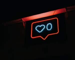A picture of a neon sign in a dark room with a heart and the number zero next to it.