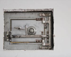 A picture of a safe inside a wall where the drywall has been cut for the opening.