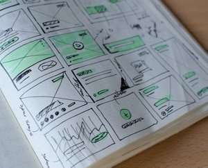 Picture of a sketch book with drawings of boxes in a grid to depict website concepts.