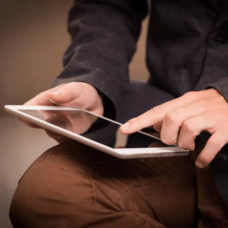 Picture of a person balancing a tablet in their knee while scrolling.