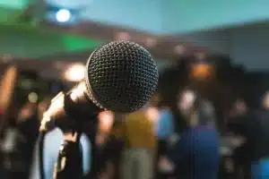Picture of a microphone with a blurry crowd in the background. 