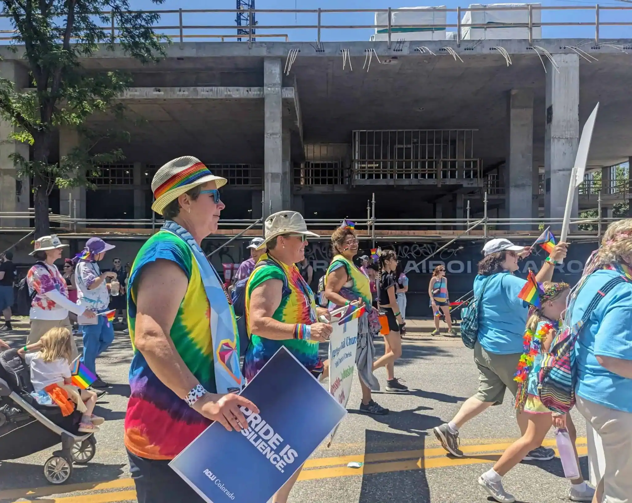 People participating in a pride parade holding rainbow flags and signs.
